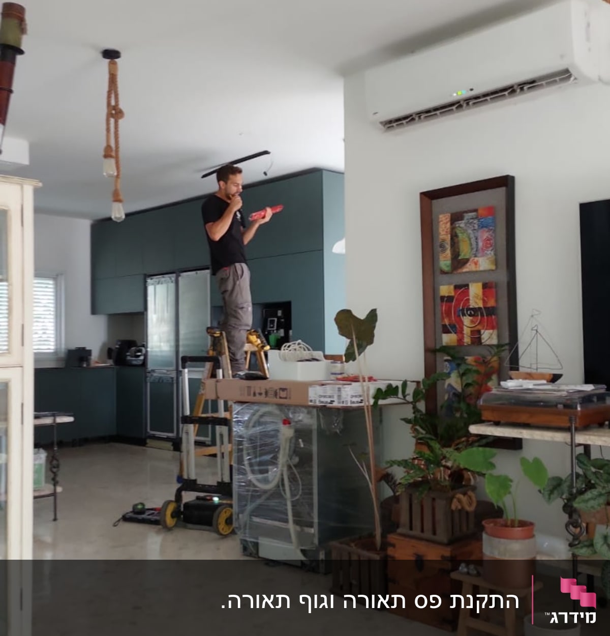 חשמלאי עומד על סולם ומתקן תאורה בתקרה